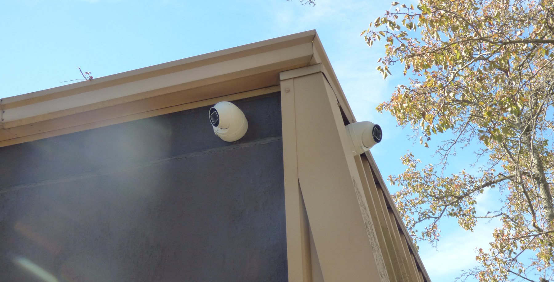 Two white turret cameras mounted at a building corner