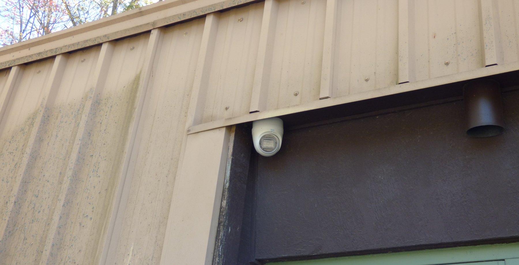White turret camera under metal trim above a door